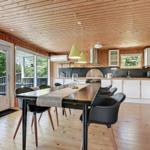 Kitchen and dining area with wooden floor and ceiling, white cabinetry, and large table with chairs.