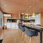 Kitchen with dining area, wooden ceiling and floor, white cabinets, black countertop, and dining table with chairs.