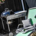 Grill and lounge chair with pillow and blanket in the garden.