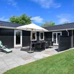 Black house with patio, umbrella, grill, and lawn.