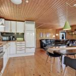Kitchen with dining area and living room under wooden ceiling.