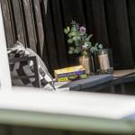 Outdoor seating area with book and floral arrangement against dark wooden fence.