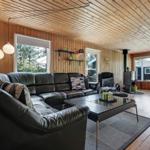 Living room with leather sofa, glass table, and wood walls. Access to kitchen.