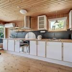 Modern kitchen with wooden ceiling, white cabinets, and built-in stove.