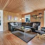 Living room with wood walls, L-shaped sofa, and glass table