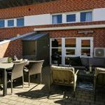 Terrasse mit Sitzgruppe, Tisch und Grill vor einem Backsteinhaus.