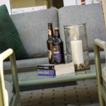 Gelber Sitzbereich mit Tisch, darauf Bücher, Flaschen und eine brennende Kerze.