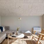 Wohnzimmer mit Sofa, Tisch und Stühlen. Große Fenster und Wandbild.