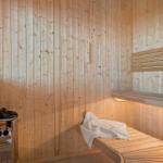 Sauna mit Holzwand, Sitzbank und Heizgerät. Ein Handtuch liegt auf der Bank.