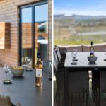 Terrasse mit Tisch, Stühlen, Wein und Snacks. Blick auf Landschaft.