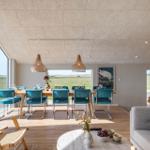 Esszimmer mit blauen Stühlen und großem Fenster. Wohnbereich mit Sofa und runden Tisch.