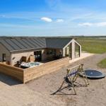 Moderne Villa mit Whirlpool, Trampolin und Spielplatz auf sandigem Grundstück.