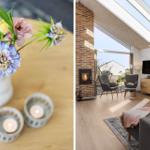 Ein Wohnzimmer mit Kamin, großen Fenstern und Dachfenstern. Blumen und Kerzen auf einem Tisch.