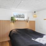 Schlafzimmer mit Bett, Holzwand und Fenster. Decke mit Lampe und Pflanze.