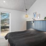 Schlafzimmer mit Bett, Wandverkleidung und Fenster zur Außenterrasse.