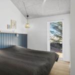 Schlafzimmer mit Bett, Fenster und Wandverkleidung.