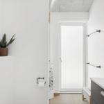 Badezimmer mit Toilette, Waschtisch und Dusche. Auf der Wand steht eine Pflanze.
