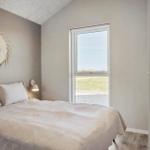 Schlafzimmer mit Bett, Wanddekoration und Fensterblick auf Grünfläche