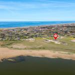 Luftbild von Strandhaus mit Blick auf Meer und Windkraftanlagen