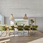 Esszimmer mit grünen Stühlen, Holztisch und großen Fenstern mit Blick auf Landschaft.