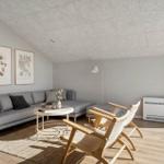 Ein Wohnzimmer mit grauem Sofa, zwei Holzstühlen und einer runden Tischplatte.