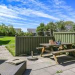 Hinterhof mit Picknicktisch, Sitzbank und grünem Zaun. Grasfläche und Bäume im Hintergrund.