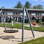 Kinderspielplatz mit Schaukel und Sandkasten vor Ferienwohnungen.
