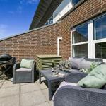 Terrasse mit Sitzgruppe, Grill und Fenstern an Backsteinwand.