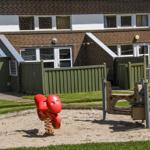 Spielplatz mit rotem Schaukelgerät und Sandkasten vor Wohnhaus