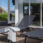 Terrasse mit Liegestühlen und Blick ins Haus. Graue Decke liegt auf einem Stuhl.