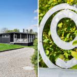 Schwarzes Haus mit Terrasse und grünem Garten. Metall-Symbol im Busch.