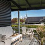 Terrasse mit Hängesessel, Sofa und Pflanze. Blick auf Garten und Nachbarhaus.