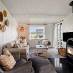 Wohnzimmer mit Sofa, Sessel, Kamin und Fenster zur Aussicht.