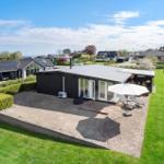 Moderne Villa mit Terrasse, Garten und Meerblick. Weiße Sonnenschirm und Liegen.