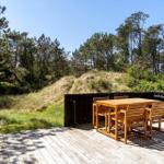Holzterrasse mit Tisch und Stühlen. Blick auf grüne Wiesen und Bäume.