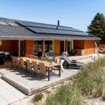 Holzhaus mit Terrasse, Esstisch, Liegestühlen und Hängematten im Strandbereich.