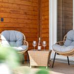 Zwei Sessel mit Kissen und Tisch mit Weinflasche auf Terrasse.