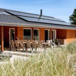 Holzhaus mit Solaranlage und Terrasse mit Tisch und Stühlen.