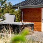 Haus mit Holzwand, Terrasse und Whirlpool im Garten.
