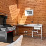 Außenküche mit Grill und Waschbecken an Holzwand
