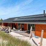 Holzhaus mit Terrasse, Liegen und Hängematten. Dach mit Solarpanele. Umgeben von Gras und Bäumen.