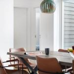 Esstisch mit braunen Stühlen und Obstschale unter einer Lampe.