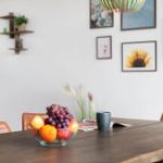 Esszimmer mit Holztisch, Obstschale und Wandbildern.