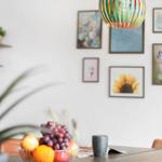 Esszimmer mit Obstschale, Wandbildern und einer hängenden Lampe.