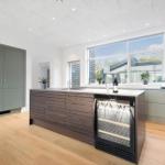 Moderne Küche mit Kücheninsel, Kühlschrank und Fenster.