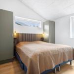 Schlafzimmer mit Bett, Kleiderschrank und Fenster mit Blick auf Bäume.