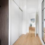 Flur mit Holzboden, Schiebetüren und Spiegeltüren. An der Wand hängen Bilder.