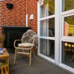 Terrasse mit Stuhl, Tisch und Pflanzen vor einer Glasfront.