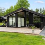 Modern wooden cabin with large deck, garden, and seating areas.