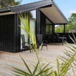 Wooden terrace with seating area in front of modern house with large window area.